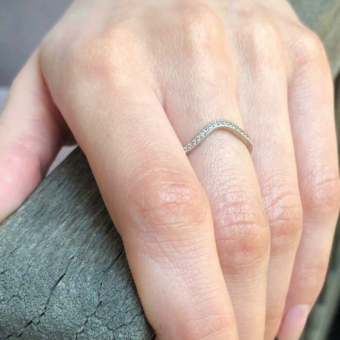 la bague Lilibeth courbe en or gris palladié et saphirs blancs portée
